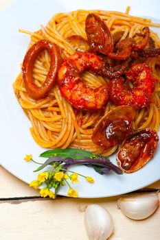 Italian seafood spaghetti pasta on red tomato sauce over white rustic wood table