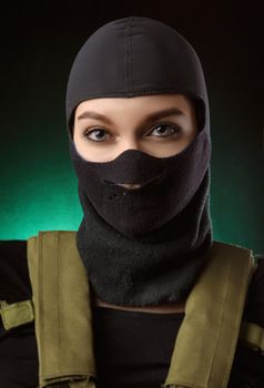 girl in military special clothes posing with a gun in his hands on a dark background in the haze