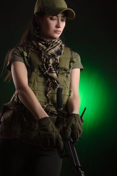 girl in military special clothes posing with a gun in his hands on a dark background in the haze