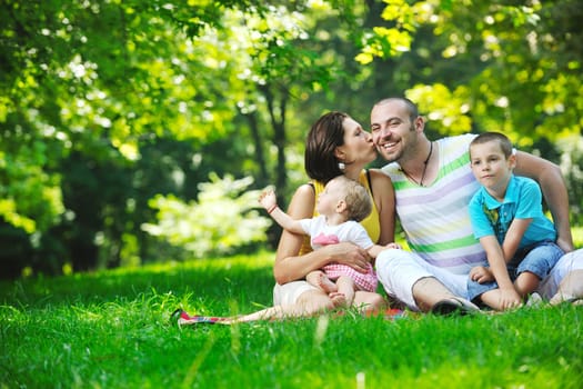 happy young couple with their children have fun at beautiful park outdoor in nature