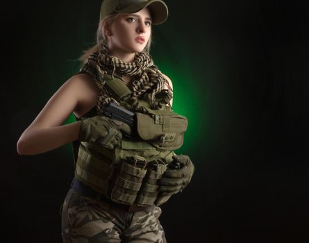 the girl in military special clothes posing with a gun in his hands on a dark background in the haze