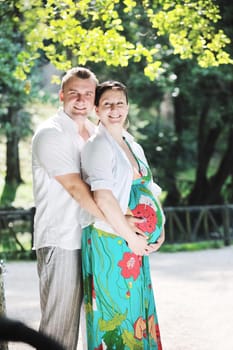 Happy pregnant couple have fun and romantic time at beautiful sunny day in park