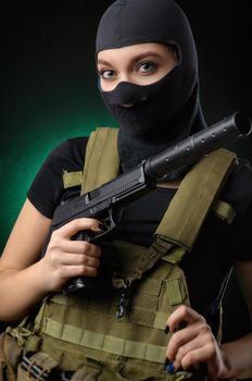 girl in military special clothes posing with a gun in his hands on a dark background in the haze