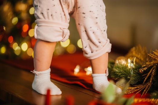 Cute little baby legs in room with Christmas tree, closeup