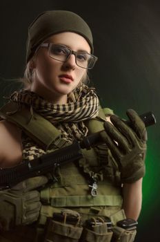 the girl in military special clothes posing with a gun in his hands on a dark background in the haze