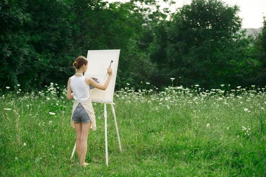 woman artist in aprons paint palette easel nature. High quality photo