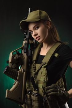 girl in military special clothes posing with a gun in his hands on a dark background in the haze