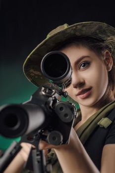 girl in military special clothes posing with a gun in his hands on a dark background in the haze