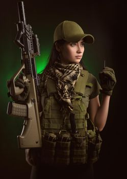 girl in military special clothes posing with a gun in his hands on a dark background in the haze