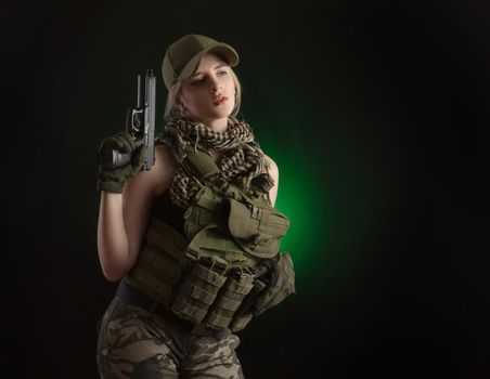 the girl in military special clothes posing with a gun in his hands on a dark background in the haze