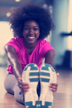 happy young african american woman in a gym stretching and warming up before workout