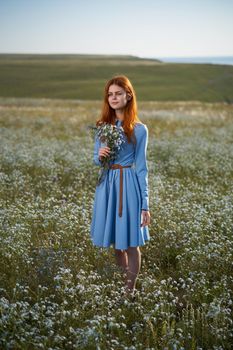 woman in a blue dress in a field in nature hat flowers walk. High quality photo