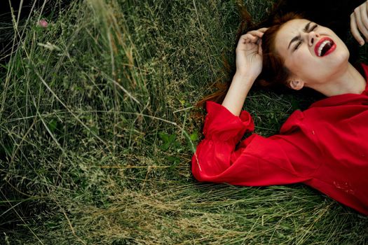 woman in red dress lies on the grass charm freedom. High quality photo