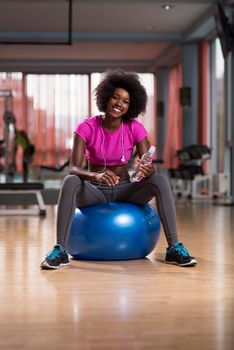 happy african american woman with a curly afro hairstyle in a  gym relaxing after pilates workout