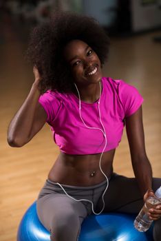 happy african american woman with a curly afro hairstyle in a  gym relaxing after pilates workout