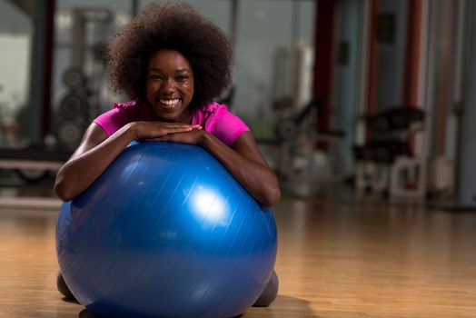 happy african american woman with a curly afro hairstyle in a  gym relaxing after pilates workout