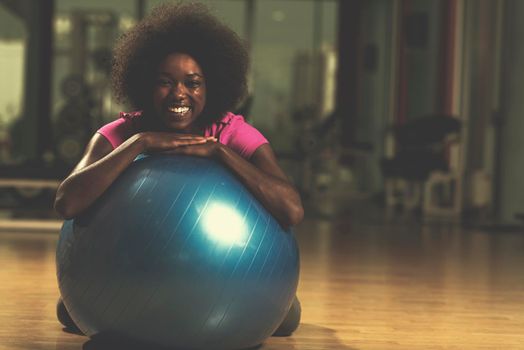 happy african american woman with a curly afro hairstyle in a  gym relaxing after pilates workout