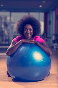 happy african american woman with a curly afro hairstyle in a  gym relaxing after pilates workout