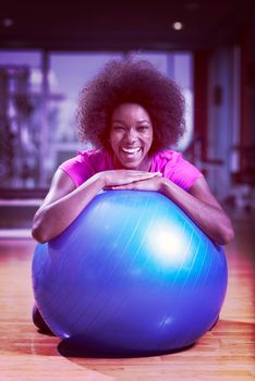 happy african american woman with a curly afro hairstyle in a  gym relaxing after pilates workout