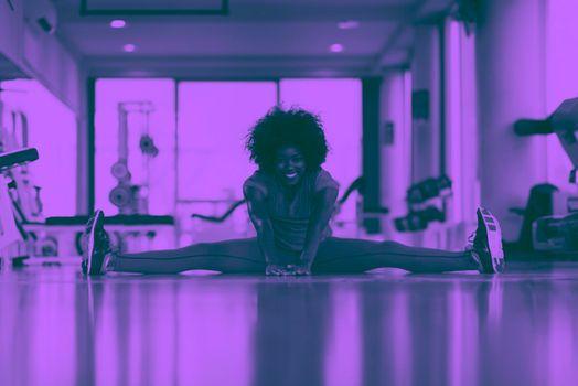 happy young african american woman in a gym stretching and warming up before workout duo tone filter