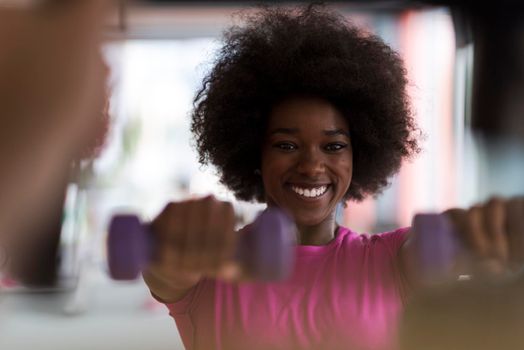 happy healthy african american woman working out in a crossfit gym on weight loss with dumbbells