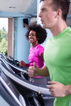 young people exercisinng a cardio on treadmill running chine in modern gym