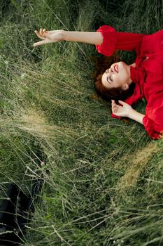 woman in red dress lies on the grass fresh air nature freedom. High quality photo