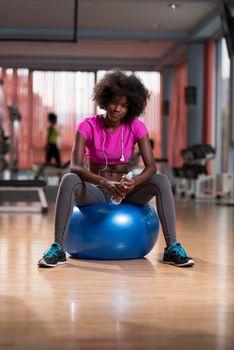 happy african american woman with a curly afro hairstyle in a  gym relaxing after pilates workout