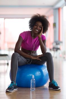 happy african american woman with a curly afro hairstyle in a  gym relaxing after pilates workout