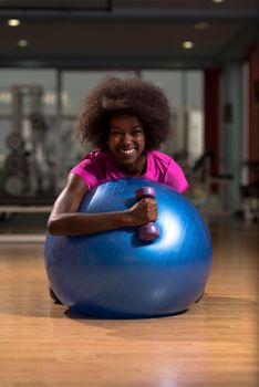 happy african american woman with a curly afro hairstyle in a  gym relaxing after pilates workout