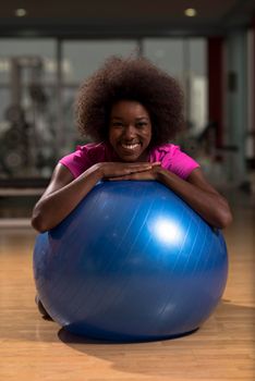 happy african american woman with a curly afro hairstyle in a  gym relaxing after pilates workout