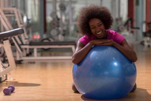 happy african american woman with a curly afro hairstyle in a  gym relaxing after pilates workout