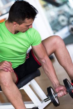 young handsome man working out with dumbbells in a fitness gym