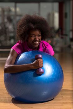 happy african american woman with a curly afro hairstyle in a  gym relaxing after pilates workout