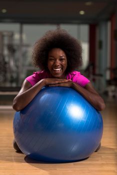 happy african american woman with a curly afro hairstyle in a  gym relaxing after pilates workout