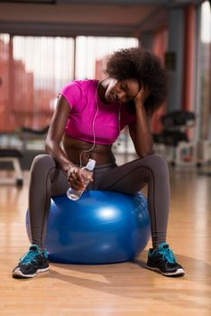 happy african american woman with a curly afro hairstyle in a  gym relaxing after pilates workout