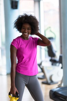 happy healthy african american woman working out in a crossfit gym on weight loss with dumbbells