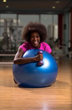 happy african american woman with a curly afro hairstyle in a  gym relaxing after pilates workout