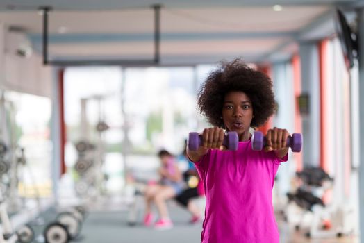 happy healthy african american woman working out in a crossfit gym on weight loss with dumbbells