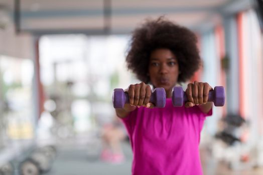 happy healthy african american woman working out in a crossfit gym on weight loss with dumbbells