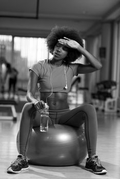 happy african american woman with a curly afro hairstyle in a  gym relaxing after pilates workout