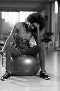 happy african american woman with a curly afro hairstyle in a  gym relaxing after pilates workout