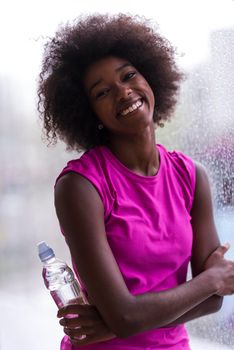 portrait of young afro american woman in gym on work out break while teaking breath and fresh water rainy day and bad weather outdooor