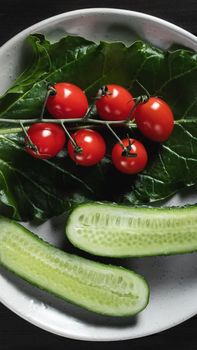 Fresh vegetables and herbs in a plate on a wooden table. Concept of vegetarianism and healthy eating.