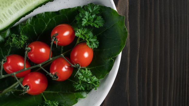 Fresh vegetables and herbs in a plate on a wooden table. Concept of vegetarianism and healthy eating. Copyspace