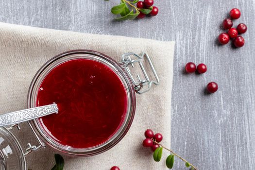 Glass jar with homemade lingonberry sauce. Canning lingonberry sauce, top view, flat lay.