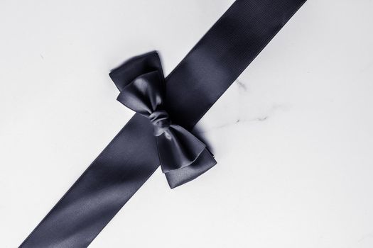 Holiday gift, decoration and sale promotion concept - Black silk ribbon and bow on marble background, flatlay