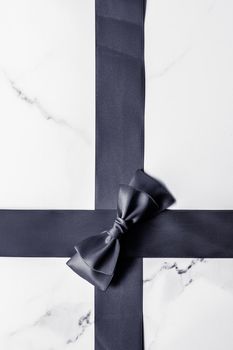 Holiday gift, decoration and sale promotion concept - Black silk ribbon and bow on marble background, flatlay