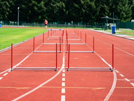 Fallen hurdle on the sprint lane with starting blocks against blurry background. Stadium with two hurdles training tracks. 