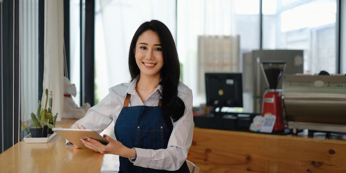 At her cafe, the business owner or barista is taking orders from customers.